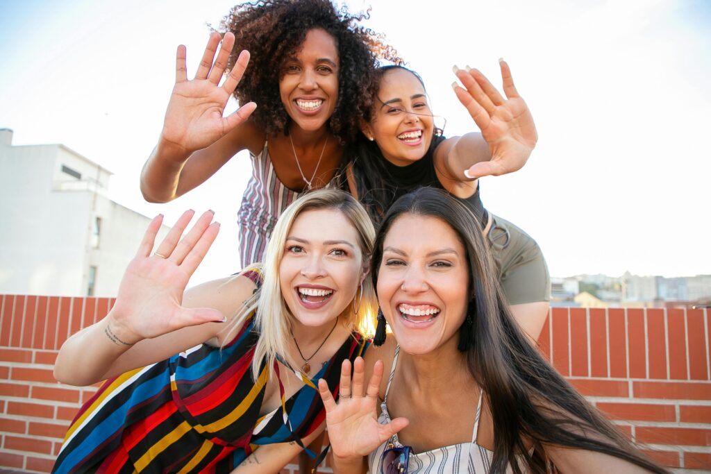 pexels-photo-5935239-5935239 A group of diverse friends enjoying a sunny rooftop hangout, waving and smiling joyfully.